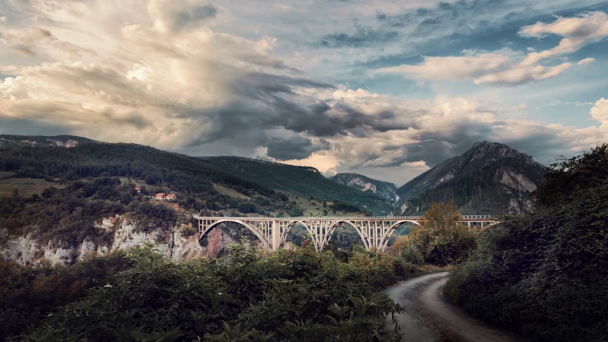 A dramatic bridge spanning a deep canyon at dusk
